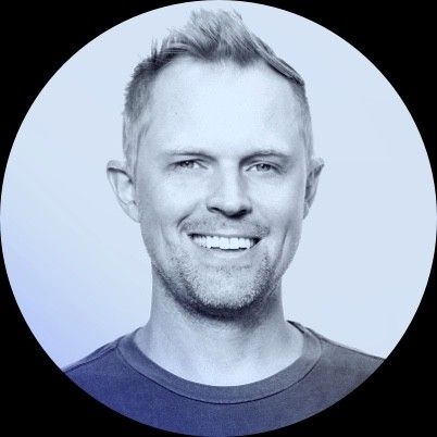 Smiling person with short hair in a blue-toned circular portrait.